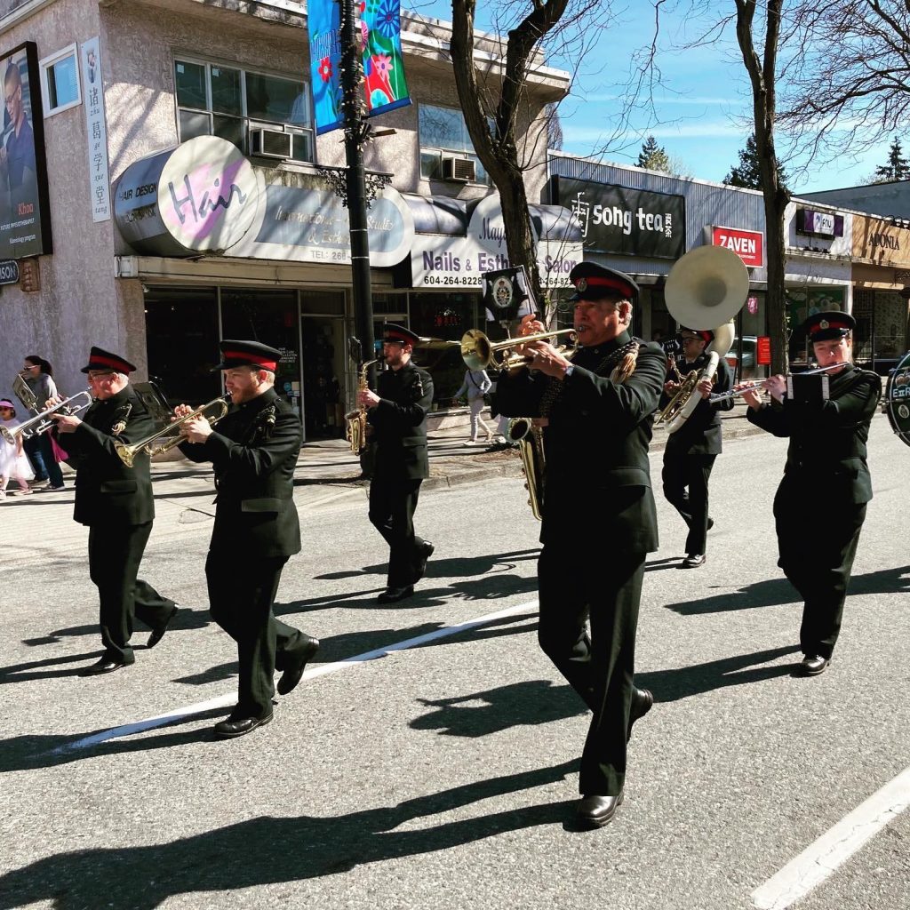 Trumpets, saxophones, a flute, and a sousaphone marching in the 2023 Kerrisdale Little League parade